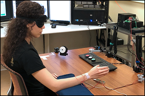 blindfolded woman with electrodes on her hand